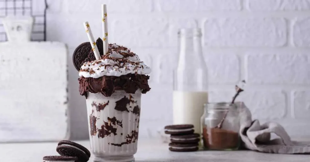 A cookies and cream milkshake with cookies and whipped cream in it.