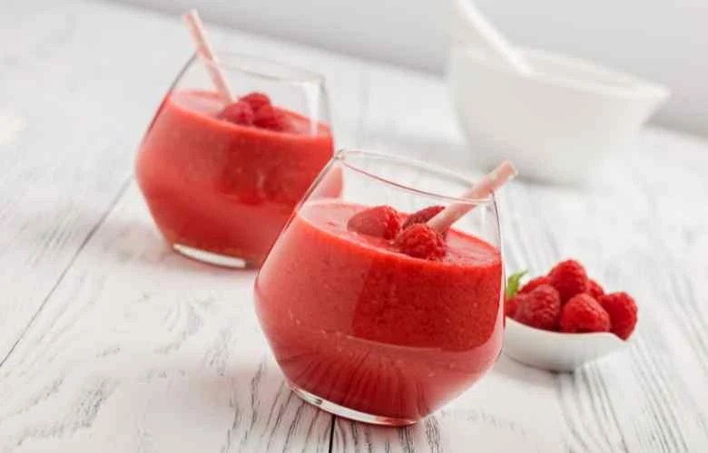 Two glasses of raspberry smoothie, also known as raspberry milkshake, on a white table, a refreshing and vibrant drink.