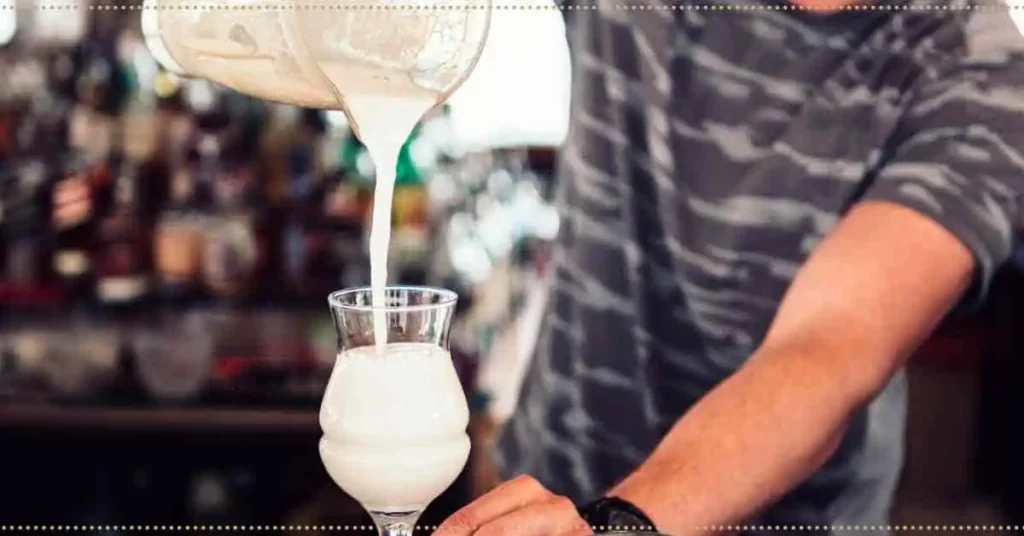 A man pouring a coconut milkshake into a glass.